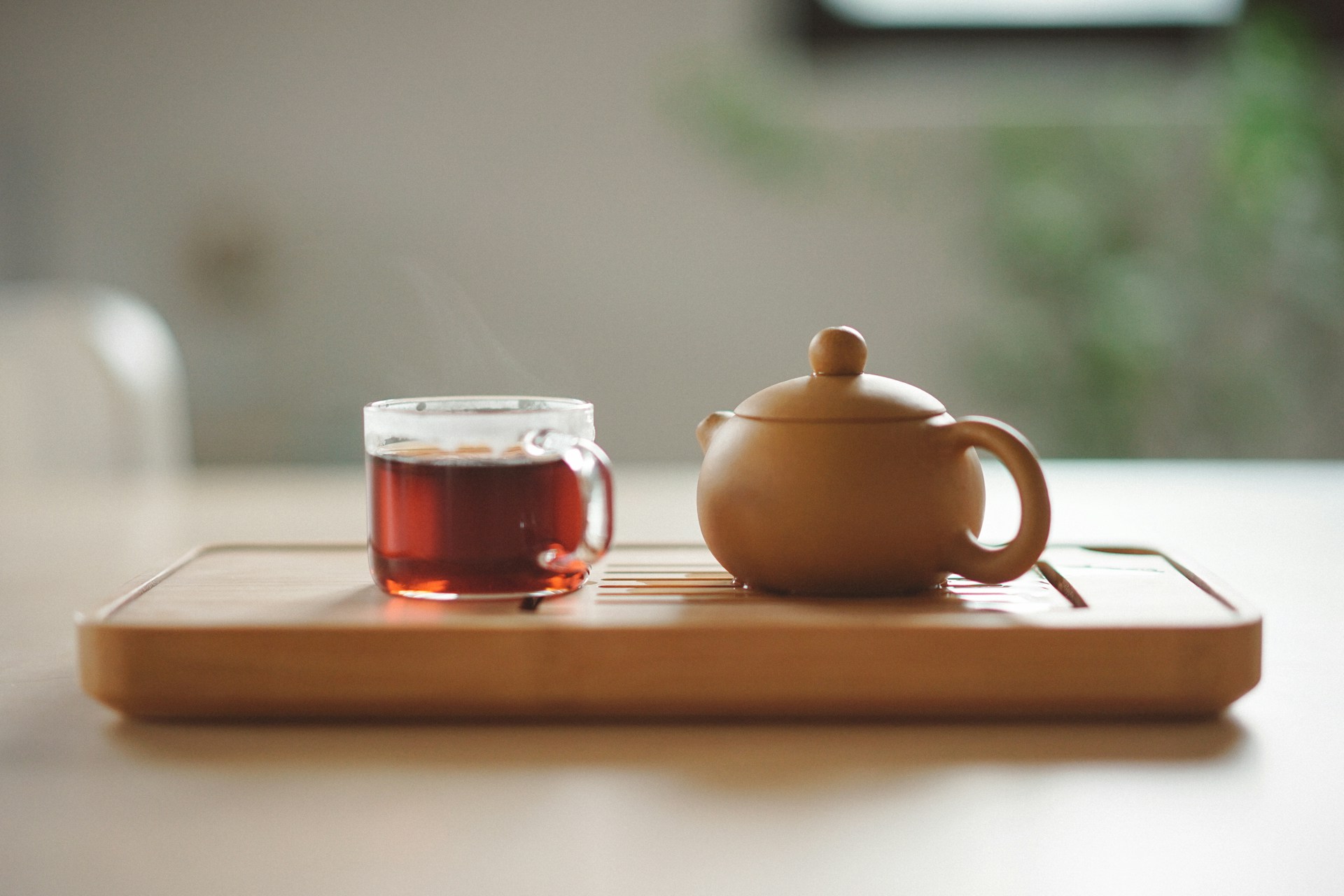 Clear glass cup with tea near brown ceramic teapot